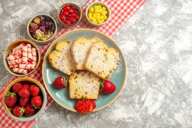 Vista superior de las rebanadas de pastel con fresas frescas y dulces en el piso de luz pastel de frutas dulces