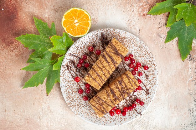 Vista superior de las rebanadas de pastel con glaseado de choco y frutos rojos sobre piso ligero pastel de galletas dulce