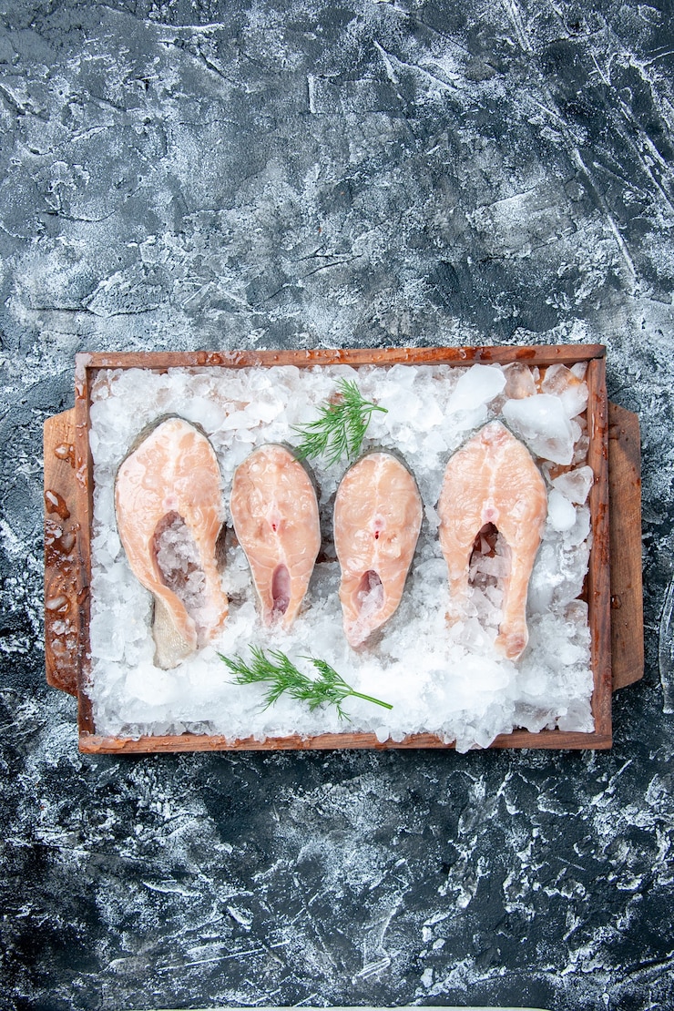 Foto gratuito vista superior rebanadas de pescado crudo con hielo en tablero de madera sobre fondo gris con espacio libre