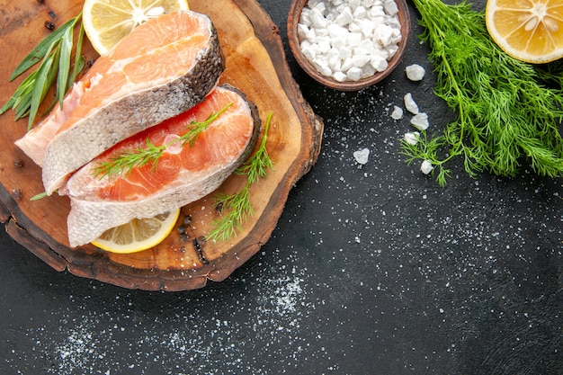 Vista superior de las rebanadas de pescado fresco con rodajas de limón en la mesa oscura plato de mariscos color comida carne cruda