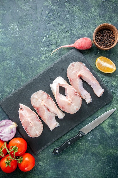 Foto gratuita vista superior rebanadas de pescado fresco con tomates rojos en una mesa azul oscuro carne de mar comida de marisco plato de agua de pimienta comida de mar