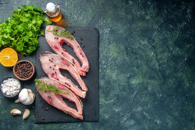 Vista superior rebanadas de pescado fresco con verduras sobre fondo azul oscuro