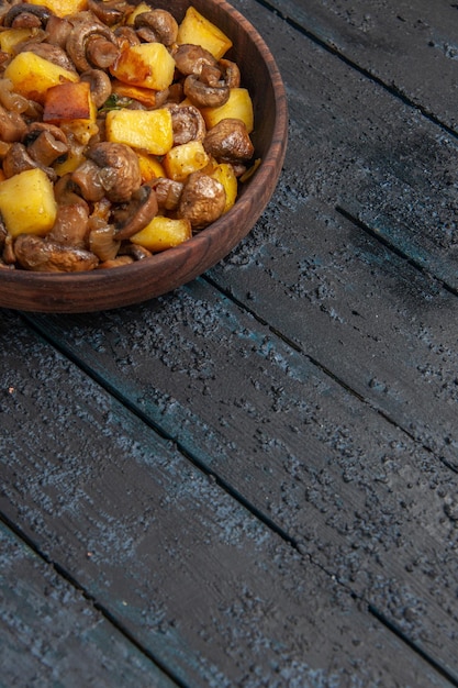 Vista superior desde un recipiente lejano con papas y champiñones en el recipiente de madera en la parte superior izquierda de la mesa.