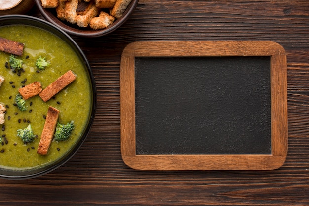 Foto gratuita vista superior del recipiente con sopa de brócoli de invierno y pizarra