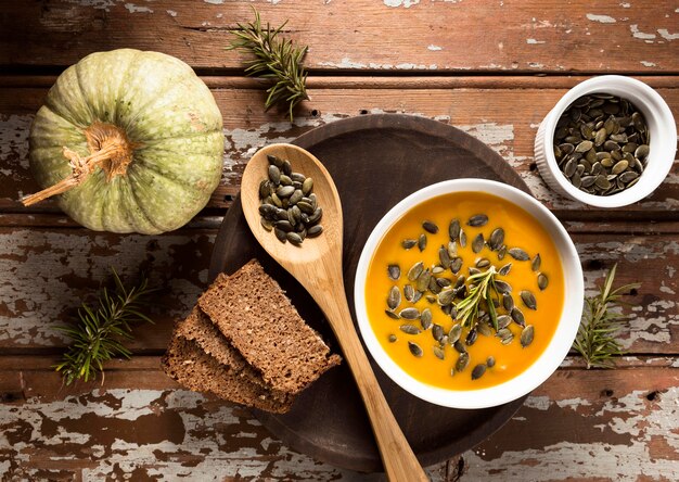 Vista superior del recipiente con sopa de calabaza de otoño con semillas y pan