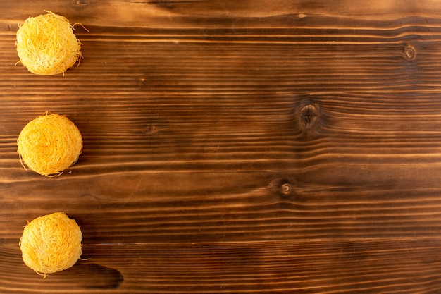 Una vista superior redonda pasteles dulces deliciosos pasteles sabrosos aislados alineados en el escritorio rústico de madera marrón galletas dulces de azúcar