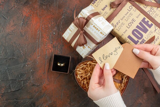 Vista superior regalos del día de san valentín con anillo y galletas sobre fondo marrón oscuro color regalo sensación matrimonio pareja de vacaciones