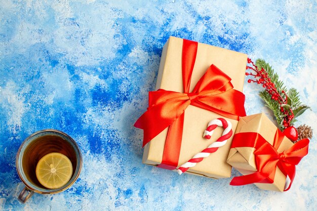 Foto gratuita vista superior de los regalos de navidad atados con una taza de té de lazo rojo en el espacio libre de la mesa azul