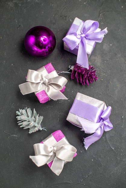 Foto gratuita vista superior de regalos de navidad de color rosa y morado con cintas juguetes de árbol de navidad en la superficie oscura aislada de navidad