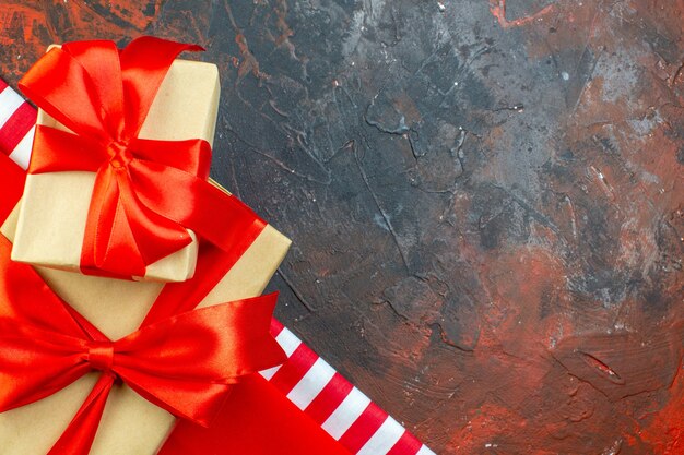 Vista superior de regalos navideños atados con cinta roja en el espacio libre de la mesa de color rojo oscuro