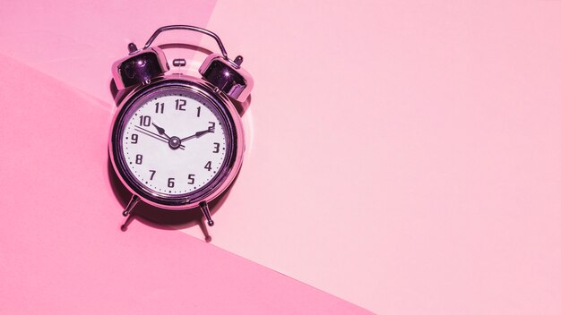 Vista superior reloj sobre fondo rosa