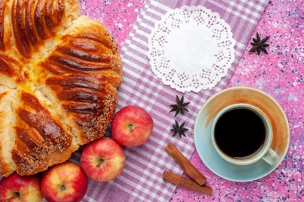 Vista superior de repostería al horno con manzanas canela y una taza de té en el escritorio rosa.