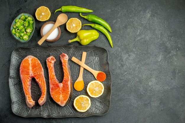 Vista superior de rodajas de carne frita con pimientos y limón sobre el fondo oscuro