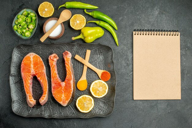 Vista superior de rodajas de carne frita con pimientos y limón sobre el fondo oscuro