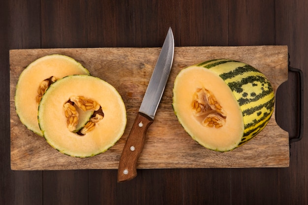Vista superior de rodajas frescas de melón cantalupo en una tabla de cocina de madera con cuchillo sobre una superficie de madera