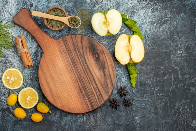 Vista superior de rodajas de manzana fresca limón y tabla de cortar de madera limas canela sobre fondo gris