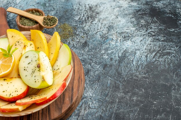 Vista superior de rodajas de manzana roja verde amarillo fresca en un plato blanco con limón sobre una tabla de cortar de madera