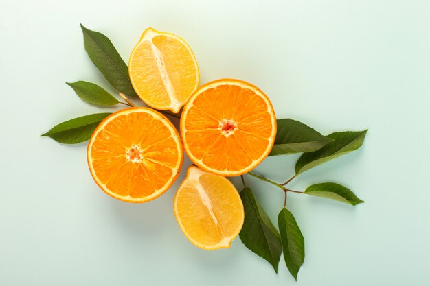 Una vista superior en rodajas de naranja fresca madura jugosa melosa aislada a medias piezas cortadas junto con rodajas de limones y hojas verdes sobre el fondo blanco color de la fruta cítricos