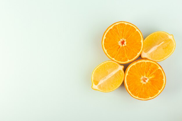 Una vista superior en rodajas de naranja fresca madura jugosa melosa aislada piezas de medio corte junto con limones en rodajas en el fondo blanco cítricos de color de fruta