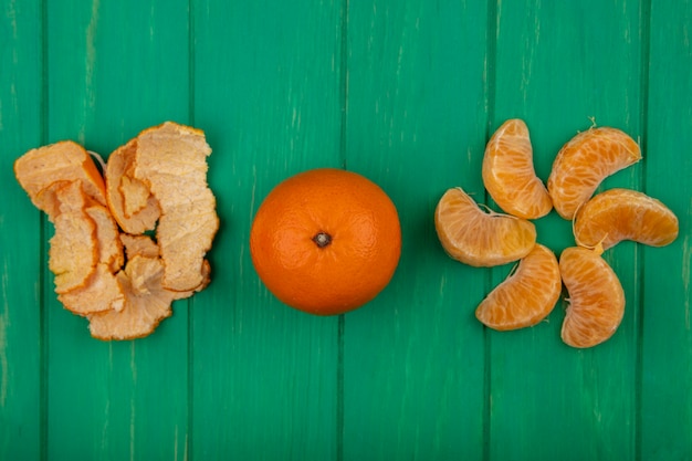 Foto gratuita vista superior de rodajas de naranja peladas con cáscara sobre un fondo verde