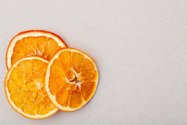 Vista superior de rodajas de naranja secas dispuestas sobre fondo blanco con espacio de copia