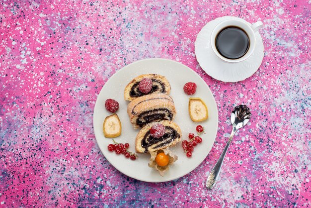 Vista superior de rodajas de pastel de rollo con diferentes frutas dentro de un plato blanco junto con una taza de café en el color dulce de la galleta de la torta de fondo de color