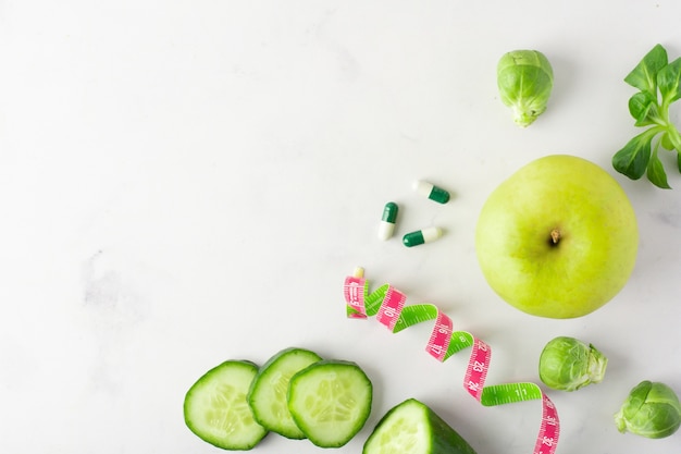 Vista superior de rodajas de pepino con manzana y cápsulas