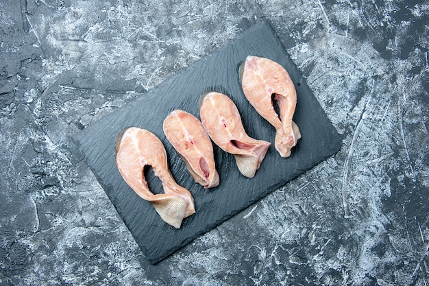 Vista superior de las rodajas de pescado crudo en la pizarra en el espacio libre de la mesa