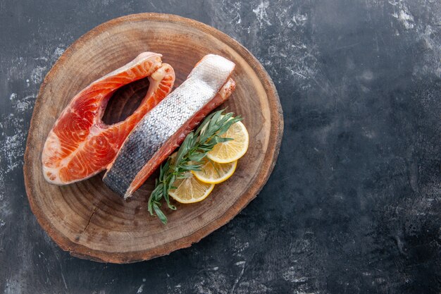 Vista superior de las rodajas de pescado con rodajas de limón sobre fondo gris