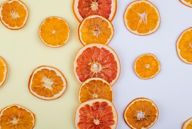 Vista superior de rodajas secas de naranja y pomelo dispuestas sobre fondo blanco.