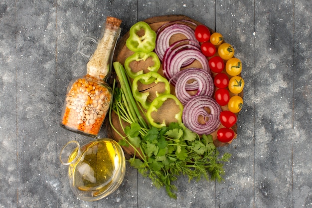 Foto gratuita vista superior rodajas de verduras enteras de colores frescos en el escritorio marrón y piso gris