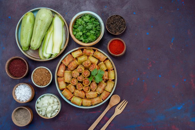 Vista superior de rollos de carne enrollados con verduras dentro de una sartén con condimentos verdes en el escritorio oscuro carne cena comida vegetal