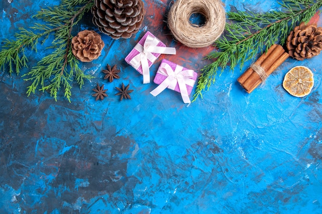 Vista superior rosa regalos de navidad ramas de pino ramas de canela anís rodajas de limón secas en la superficie azul espacio libre