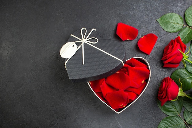 Vista superior de rosas rojas con caja llena de pétalos de rosa para el día de san valentín en el fondo oscuro amor mujer corazón sentimiento pareja color pasión