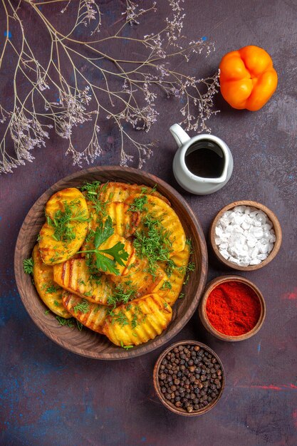 Vista superior sabrosa comida deliciosa de papas cocidas con verduras y condimentos en el piso oscuro plato de cena de papa cocinando comida