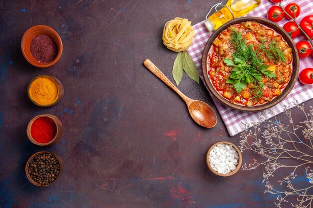 Vista superior sabrosa comida de salsa de verduras cocidas con tomates y condimentos en un plato de comida de salsa de cena de comida de fondo oscuro