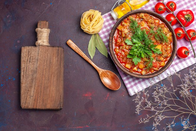 Vista superior sabrosa comida de salsa de verduras cocidas con tomates en el plato de comida de salsa de cena de comida de fondo oscuro