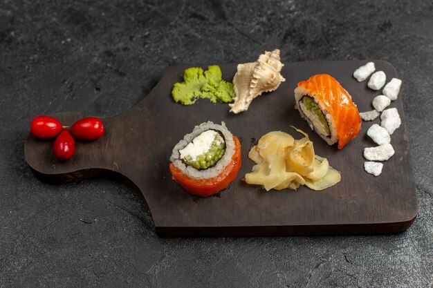 Vista superior de la sabrosa comida de sushi, rollos de pescado en rodajas con wassabi verde en la pared gris