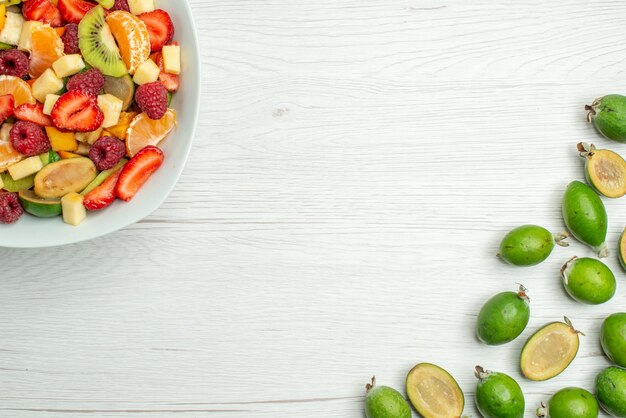 Vista superior sabrosa ensalada de frutas con feijoas frescas en el escritorio blanco