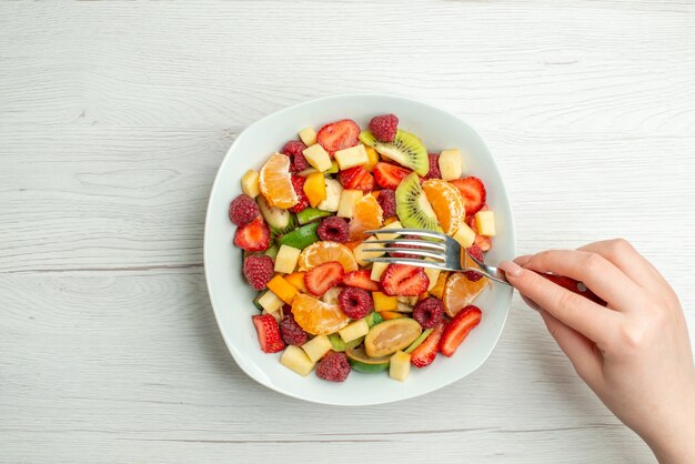 Vista superior sabrosa ensalada de frutas frutas en rodajas sobre fondo blanco.