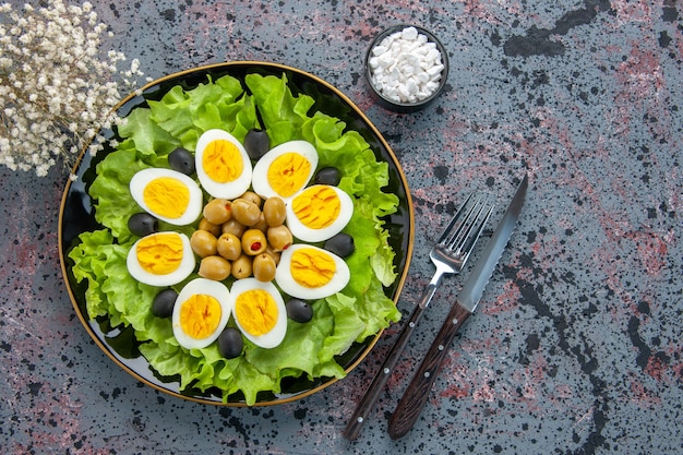 Vista superior sabrosa ensalada de huevo consiste en ensalada verde y aceitunas sobre fondo claro
