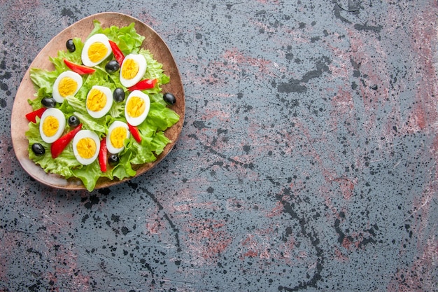 Vista superior sabrosa ensalada de huevo con ensalada verde y aceitunas dentro de la placa sobre fondo claro