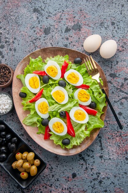 Vista superior sabrosa ensalada de huevo con ensalada verde y aceitunas sobre fondo claro