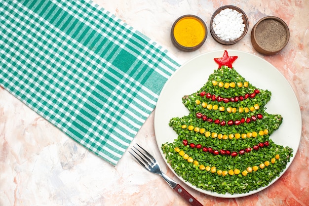 Vista superior sabrosa ensalada verde en forma de árbol de año nuevo con condimentos sobre fondo claro