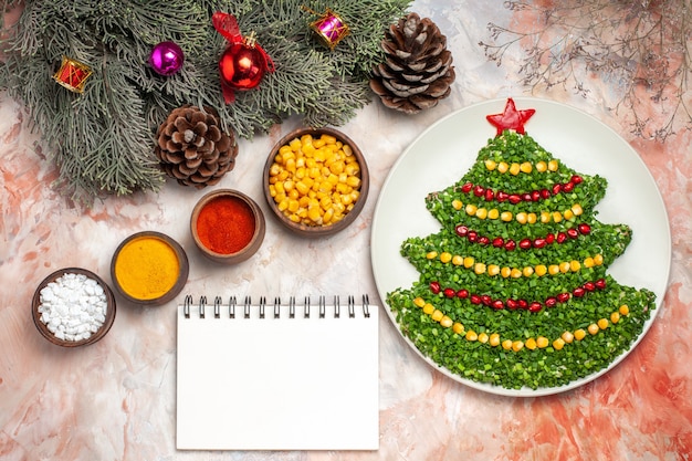 Vista superior sabrosa ensalada verde en forma de árbol de año nuevo con condimentos sobre fondo claro