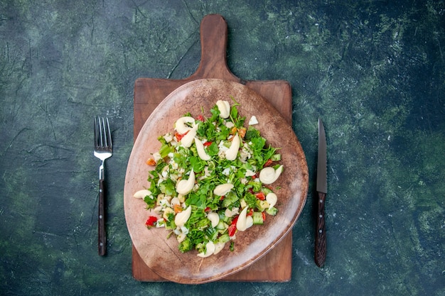 Vista superior sabrosa ensalada de verduras dentro de la placa con cubiertos sobre fondo azul oscuro cocina color de salud en forma restaurante cena cocina almuerzo comida