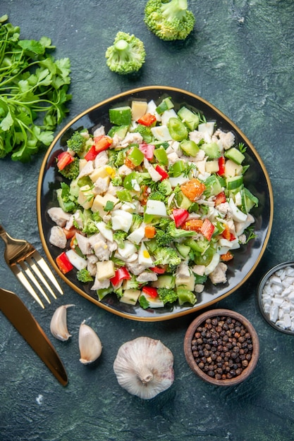 Vista superior sabrosa ensalada de verduras dentro de la placa con cubiertos sobre fondo oscuro restaurante de cocina comida fresca color salud almuerzo dieta