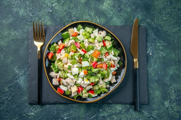 Vista superior sabrosa ensalada de verduras dentro de la placa con un tenedor sobre fondo oscuro restaurante de cocina comida fresca color salud almuerzo comida dieta