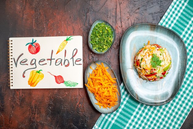 Vista superior sabrosa ensalada de verduras dentro de la placa con verduras y zanahoria en rodajas en la mesa oscura