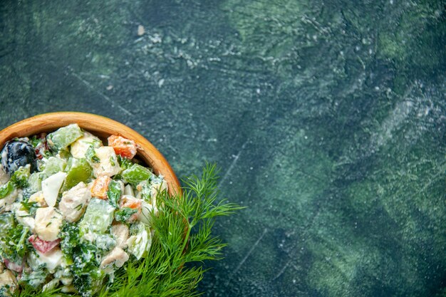 Vista superior sabrosa ensalada de verduras con mayyonaise y verduras dentro de la olla sobre fondo azul oscuro